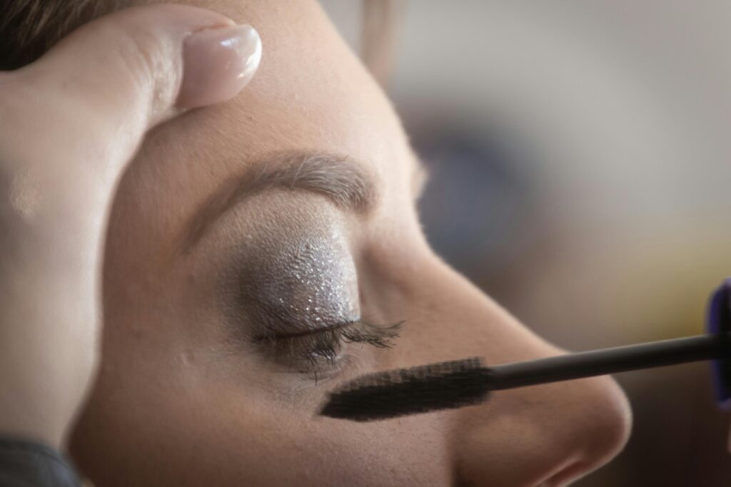 A woman's eyelid is delicately painted with glamorous shimmery eyeshadow and mascara.